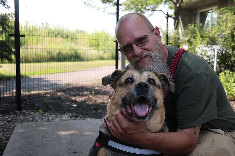 Man embracing a senior dog outdoors. 