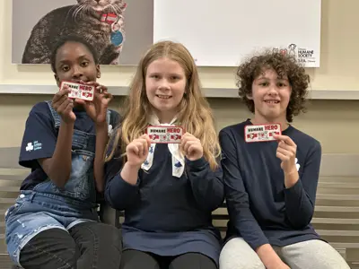 Three teens pose on a bench with their pet care crest badges