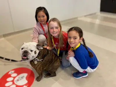 Three children crouching with a dog