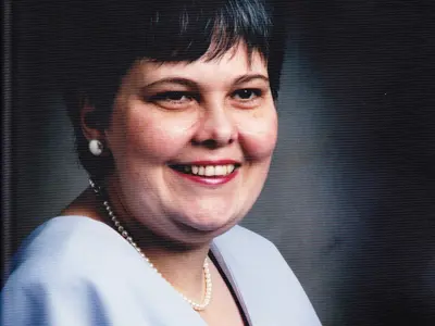 A woman smiling and wearing a blue shirt. 