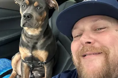 A man and a dog smiling in a car.